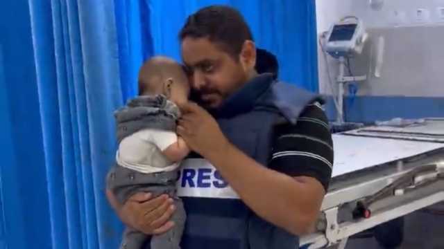 ناضل بعدسته بعد بتر قدميه.. صحفي فلسطيني يداعب طفلا وسط القصف في غزة (صور)