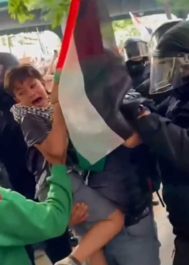 الشرطة الألمانية تحاول انتزاع علم فلسطين من يد طفل رغم بكائه في أحضان والده (فيديو)